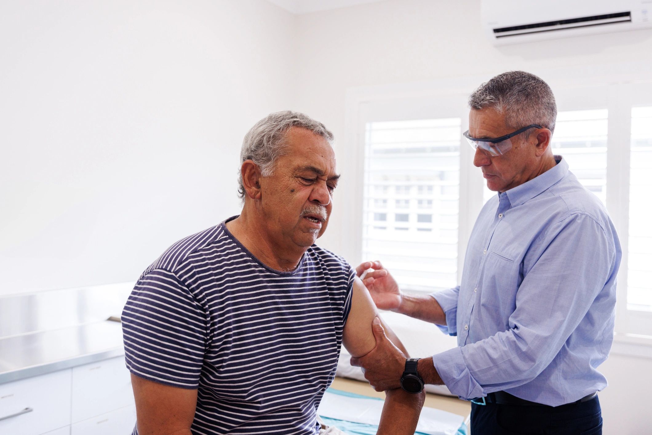 Healthcare professional supporting an older Australian man